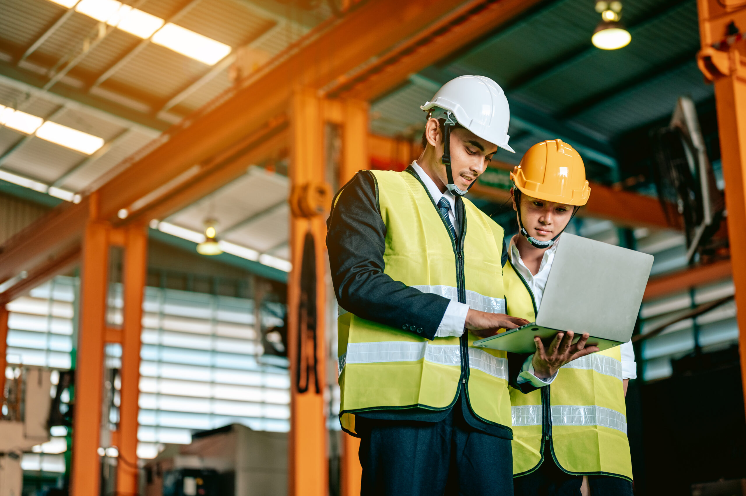Factory manager and worker with safety helmet use laptop and corporated application to discuss inspection result. Manufacturing industry teamwork concept.
